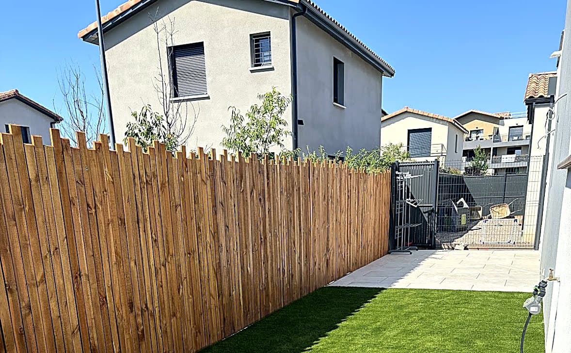 Aménagement de jardin avec gazon synthétique, terrasse et clôture bois dans le Gard